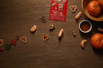 top view of fresh ripe tangerines, cup of tea and decorative golden coins on wooden surface