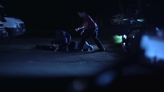 Cops patrolling streets, watching men beating innocent person, aiming for shot