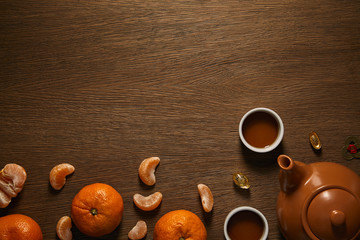 top view of tea set, tangerines and coins on wooden surface