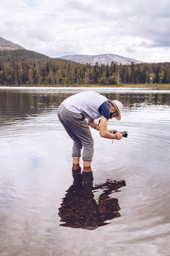Sweden, Lapland, man standing in water taking photos