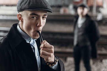 stylish man in retro outfit, smoking wooden pipe. sherlock holmes look.  england in 1920s theme....