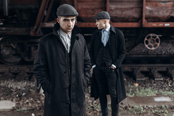brutal gangsters posing on background of railway carriage. england in 1920s theme. fashionable confident man. atmospheric moments. space for text. peaky blinders