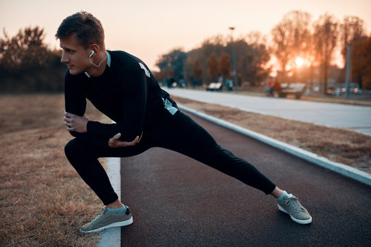 Young man stretching outdoors during sunset
