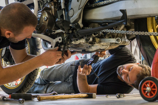 Mechanic working on motorcycle in workshop filmed by his partner