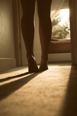 beautiful young woman walking on tiptoes towards her bedroom