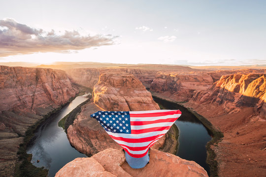 USA, Arizona, Colorado River, Horseshoe Bend, young man on viewpoint with American flag