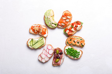 Set of colorful sandwiches prepared with different ingredients such as fish, vegetables and meat