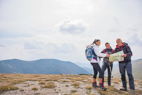 adventure, travel, tourism, hike and people concept - group of smiling friends with backpacks and map outdoors