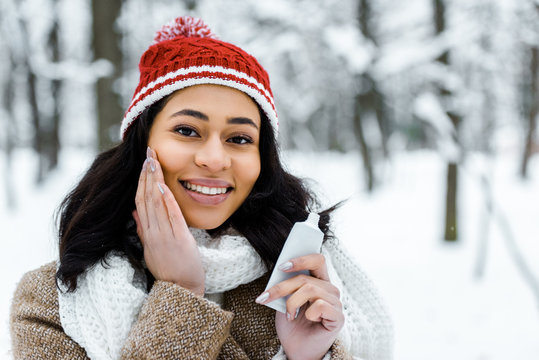 attractive african american woman touching cheek in winter forest