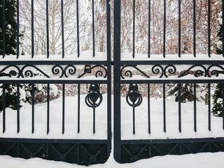 Iron gates at the entrance to the city Park. Winter day. The drifts of snow.