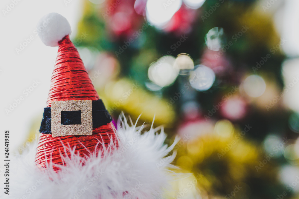 Wall mural santa claus hat with christmas tree bokeh in the background