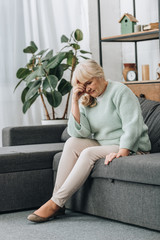 upset retired woman sitting on sofa in living room