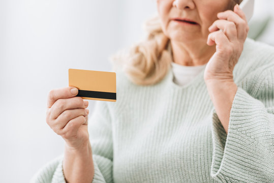 Selective Focus Of Credit Card In Hand Of Senior Woman Talking At Smartphone