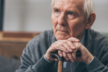 close up of retired man with grey hair holding walking cane