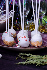 Cake pops covered in white chocolate and multicoloured sprinkles on a plate