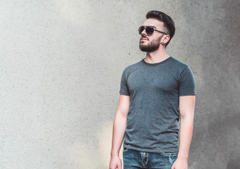 Portrait of a handsome young man standing against gray background. Youth culture. Barbershop.