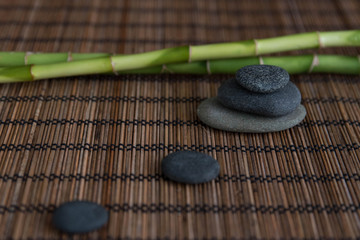 Pyramids of gray zen pebble meditation stones with green bamboo leaves and on wooden background....