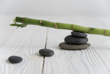 Pyramids of gray zen pebble meditation stones with green bamboo leaves and on wooden background. Concept of harmony, balance and meditation, spa, massage, relax