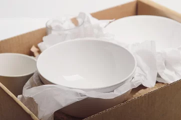 Photo sur Plexiglas Nettoyez la vaisselle blanche dans du papier emballé dans une boîte en carton. Déménagement du concept