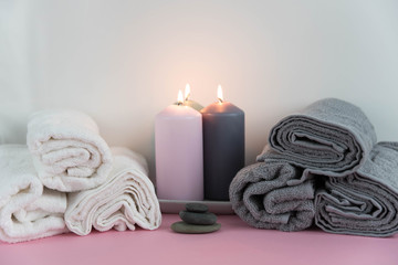 Obraz na płótnie Canvas Beautiful spa still life. Twisted towel, aromatic candles and black hot stone on wooden background. Hot stone therapy. Concept of harmony, balance and meditation, relax, massage, beauty spa treatment.