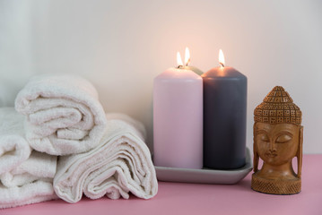 Fototapeta na wymiar Beautiful spa still life composition. Twisted towel, aromatic candles and Buddha statue. Concept of cosmetology, weight loss, cellulite, balance and meditation, relax, massage, beauty spa treatment.
