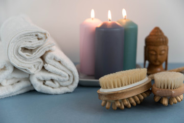 Beautiful spa still life composition. Twisted towel, aromatic candles and wooden massage brushes for body and legs. Concept of harmony, balance and meditation, relax, massage, beauty spa treatment.