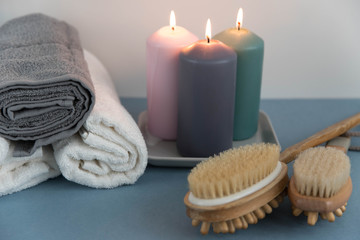 Fototapeta na wymiar Beautiful spa still life composition. Twisted towel, aromatic candles and wooden massage brushes for body and legs. Concept of harmony, balance and meditation, relax, massage, beauty spa treatment.