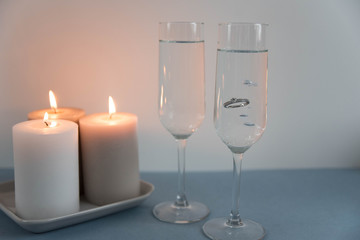 Marriage proposal and love concept for Valentine`s day with wedding or engagement ring with brilliant. Glasses of champagne and romantic candles in the restaurant