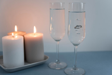 Marriage proposal and love concept for Valentine`s day with wedding or engagement ring with brilliant. Glasses of champagne and romantic candles in the restaurant
