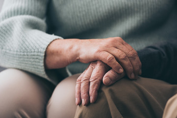 cropped view of senior woman holding hands with retired husband - obrazy, fototapety, plakaty
