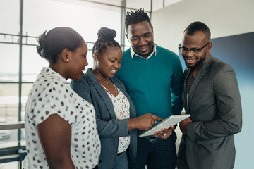 Team of african business people standing and smiling using a tablet