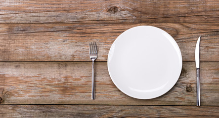 Plate, fork and knife on wooden background