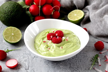 Homemade avocado smoothie served with raspberries on light background. Top view with copy space. Diet food. Vegetarian and vegan food.