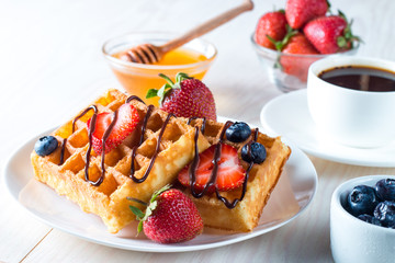 Fresh homemade food of berry Belgian waffles with honey, chocolate, strawberry, blueberry, maple syrup and cream. Healthy dessert breakfast concept with juice