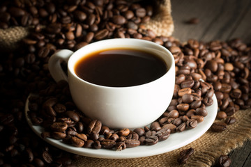 Fototapeta premium Coffee cup and beans on a rustic background. Coffee Espresso and a piece of cake with a curl. Cup of Coffee and coffee beans on table.