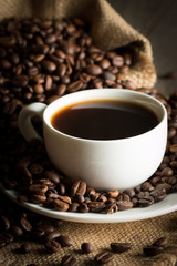Coffee cup and beans on a rustic background. Coffee Espresso and a piece of cake with a curl. Cup of Coffee and coffee beans on table.