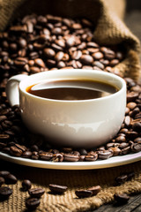 Coffee cup and beans on a rustic background. Coffee Espresso and a piece of cake with a curl. Cup of Coffee and coffee beans on table.