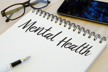 Health concept. Eyeglasses,pen,mobile phone and notebook written with Mental Health.