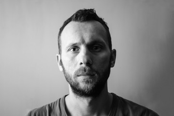 the calm face of a young man with a beard, black and white photo