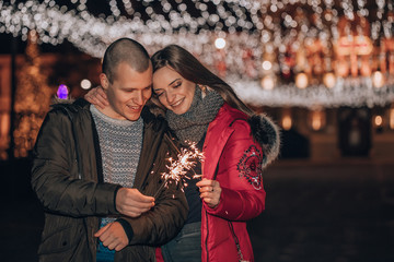 Fototapeta premium Happy couple with sparklers in winter city night