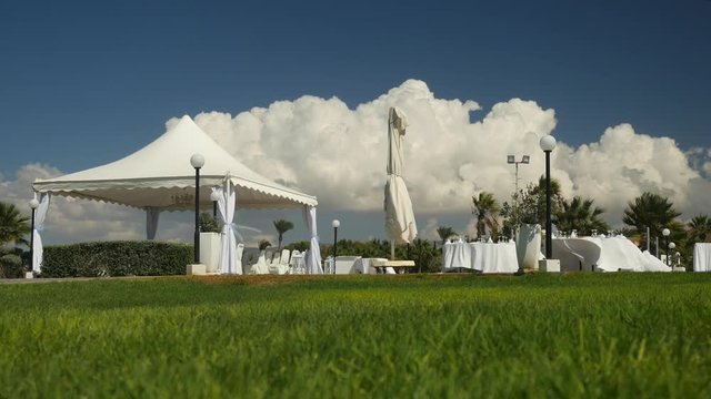 Empty buffet in nature made in white colours. Landscape is picturesque. Green grass, blue sky, empty place