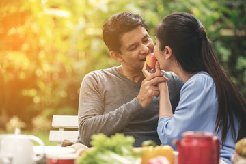 Retirement elder lover having a happy time eating an apple together, dinner in backyard. Couple having a romantic dinner.