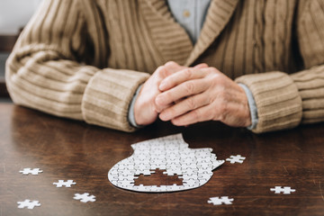 cropped view of senior man playing with puzzles on table - obrazy, fototapety, plakaty
