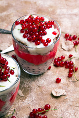 Healthy dessert with organic red currants, fresh yogurt and corn flakes. Dietary breakfast on a brown background