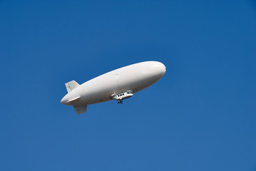 Fototapeta na wymiar Large white dirigible airship against a clear blue sky. Plenty of room for text.