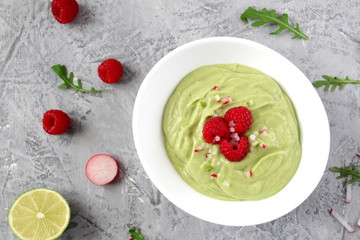 Homemade avocado smoothie served with raspberries on light background. Top view with copy space. Diet food. Vegetarian and vegan food.