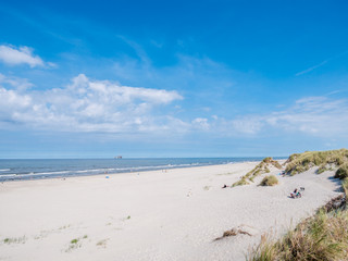 Fototapeta na wymiar People on beach and North Sea with offshore platform, West Frisian island Ameland, Friesland, Netherlands