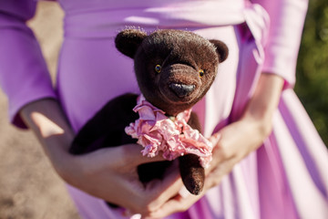 Girl in a pink dress holding a Teddy bear in her hands. Girl says goodbye MS childhood. A woman in...