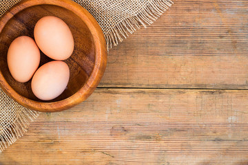Easter eggs in wooden bowl on wooden background.