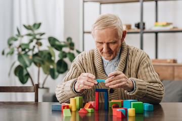 senior man playing with wooden shapes at home